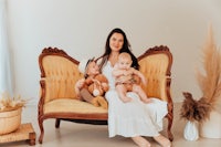 a woman sits on a yellow chair with two children